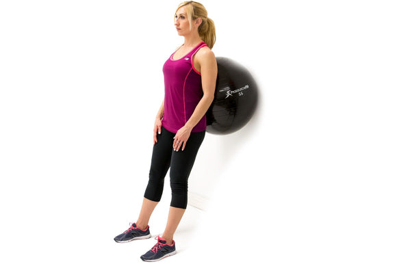 woman standing against prosourcefit stability ball in starting position of squat