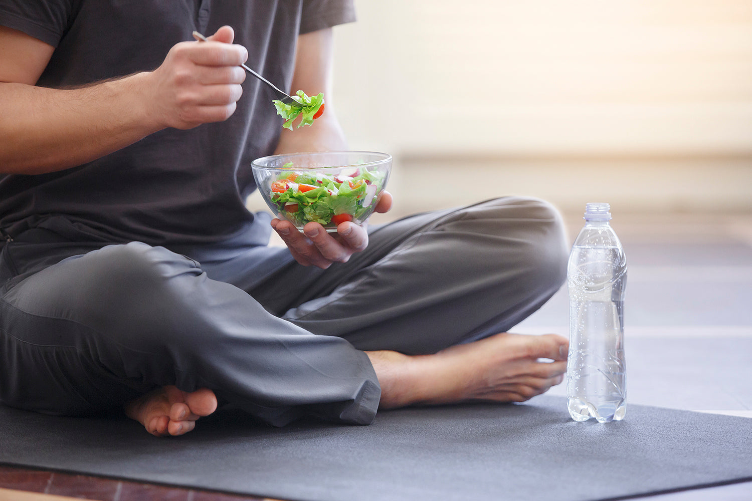 man eating salad on yoga mat