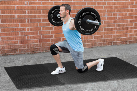 Man doing single leg lunge with Olympic Barbell and Bumper Plates