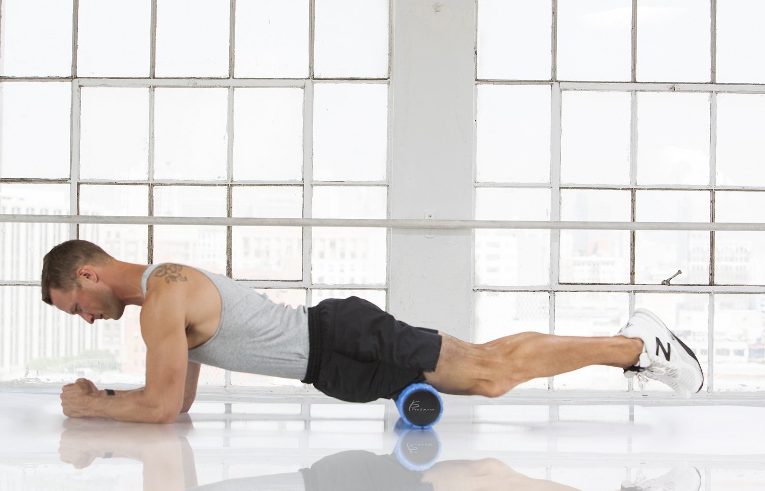 Man using a ProSource 2-in-1 Hexa Massage Roller for self-myofascial release on his thighs