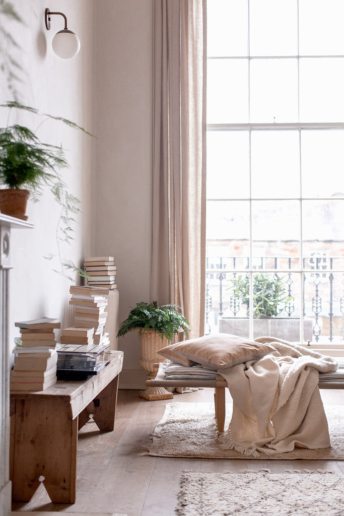 daybed surrounded by books by a big window 