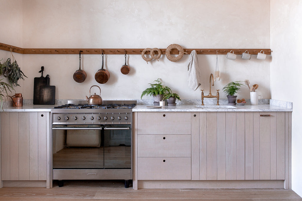 natural wooden kitchen with venetian plaster walls, brass, copper, marble and potted plants 