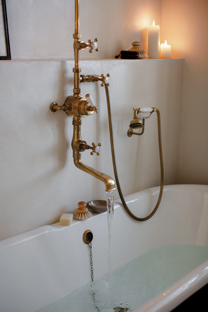 natural bathroom with claw foot bathtub and brass taps 