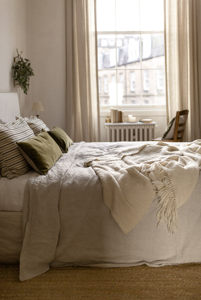 natural bedroom with jute rug, linen bedding and green