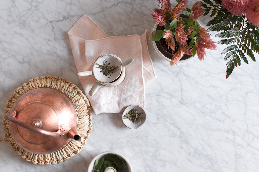 copper kettle, marble worktop pink linen napkin, handmade ceramic mug in grey 