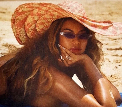 Beyonce sunbathing wearing a hat and cat-eyed style similar to TABBY sunglasses from Giant Vintage