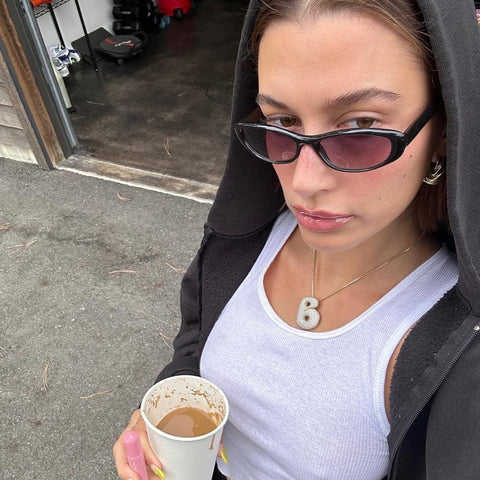 Hailey Bieber wearing a hoodie holding her coffee while posing in her Fiddle style sunglasses from Giant Vintage