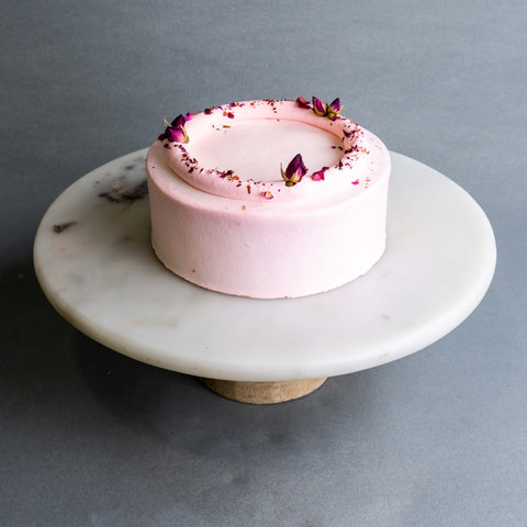 Fluffy sponge cake, coated in light pink cream, garnished with dried flowers