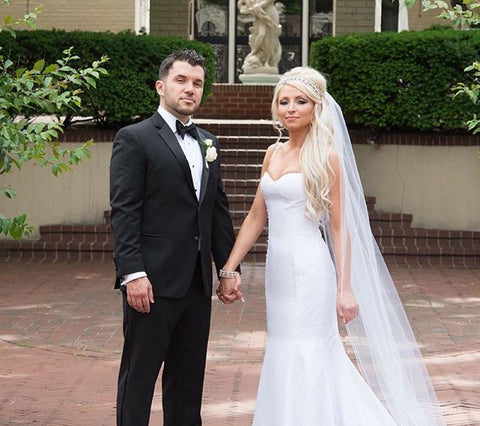 Bride and Groom with bride wearing a long white dress and veil and long blonde wavy hair extensions by Queen C Hair