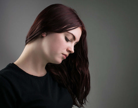 Young woman with black hair and black top look down and to the left