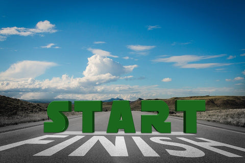 picture of a finishing line painted in white on the road, and the word start standing in block letter on the road above the word finish