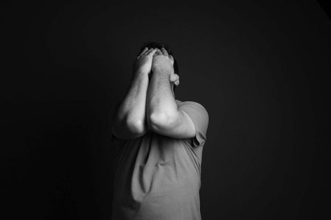 Man with hands held up to his face in despair