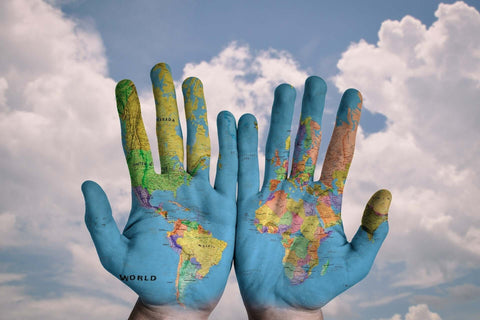 Photo of open hands palms up together with a world map painted on them