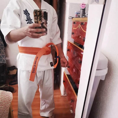A man wearing a 12oz white Kyokushin Karate Uniform sold on 100 Spartans