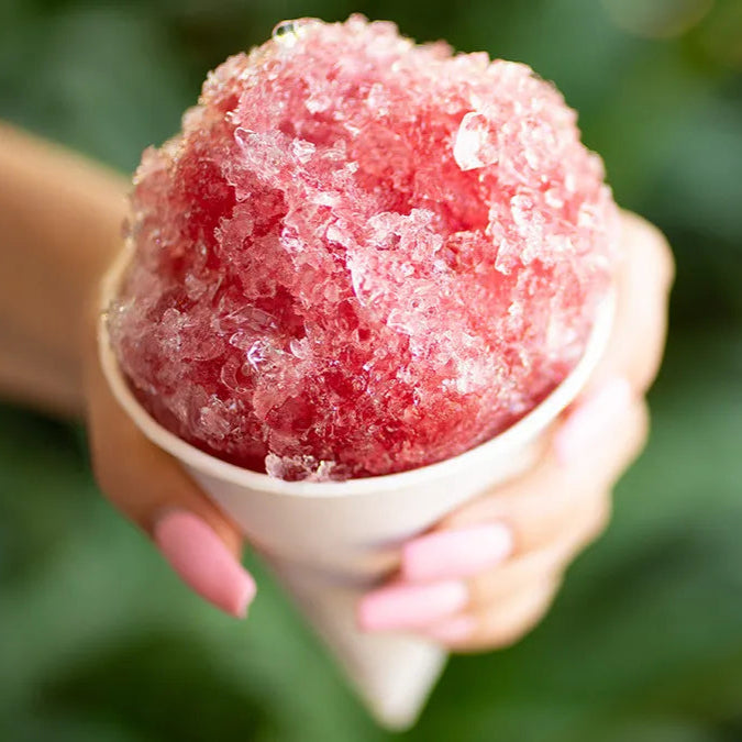 A hand holding a delicious pink snow cone, capturing a moment of happiness and indulgence.