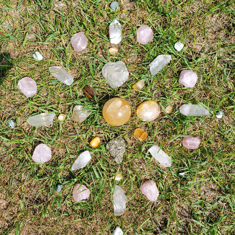 summer solstice crystal grid in the grass with yellow and clear stones and crystals