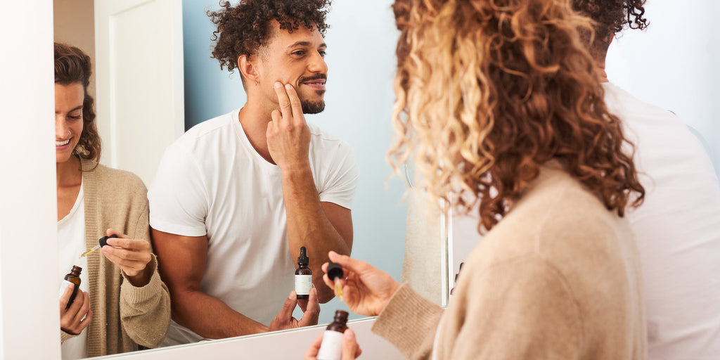 Man and woman applying OWL skincare products in mirror