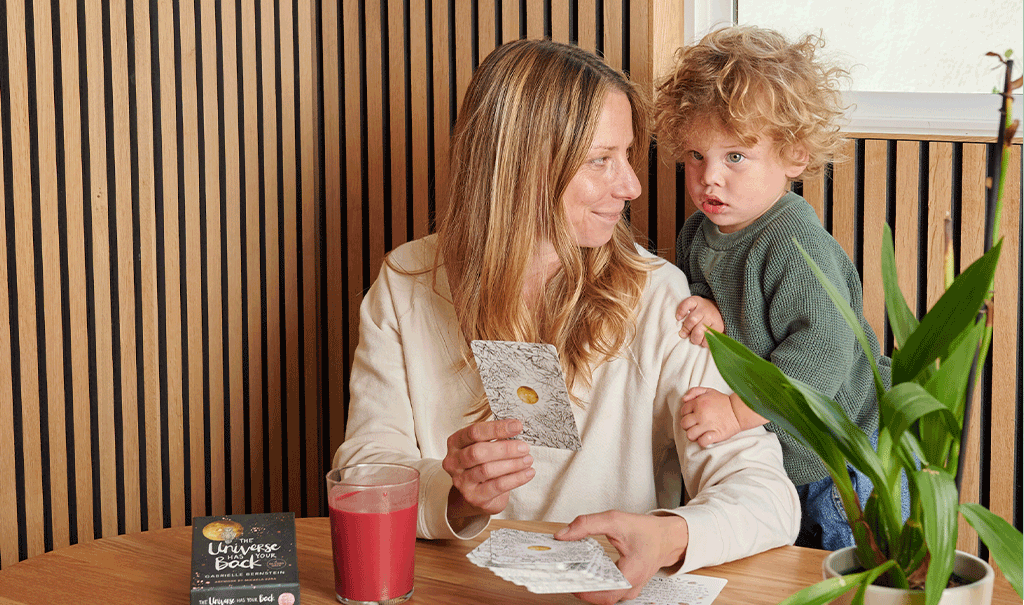 Lindsey and son using the universe has your back card deck during her spring cleanse with a bold beet hemp mylkshake
