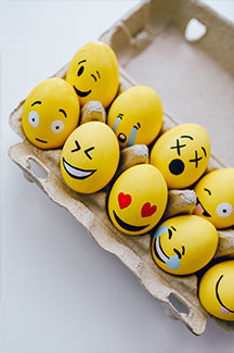 An image of a dozen eggs painted like emojis