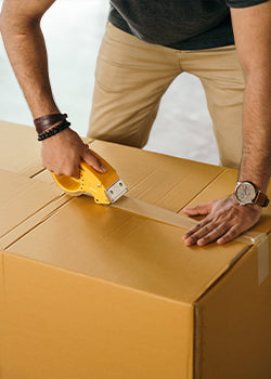 a man taping up a large cardboard box