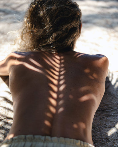 A girl laying on the beach, self tanning.