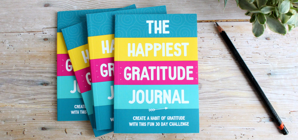 The Happiest Gratitude Journal, stack of 4 on a desk.
