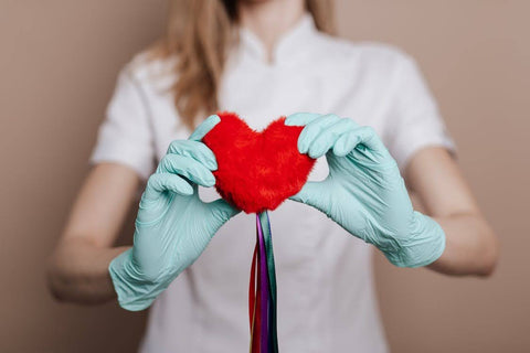 Heart Health After 50: The Best Supplements - Woman wearing medical gloves, holding a heart plushie