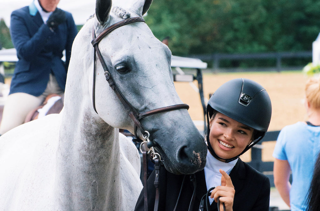 Girl smiling while holding a horse. 