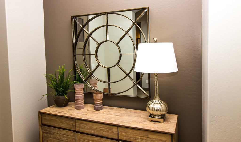 Elegant lamp and lampshade sitting on top of a wood dresser in the hallway inside a home.