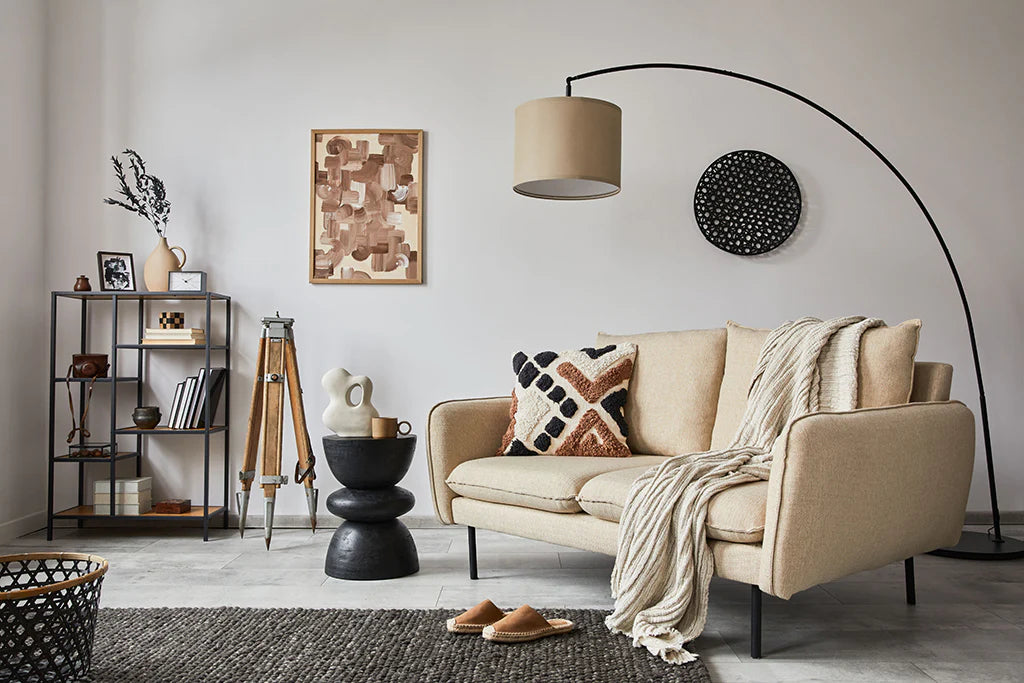 A cozy living room with black, brown and beige accents, and a matching beige lampshade