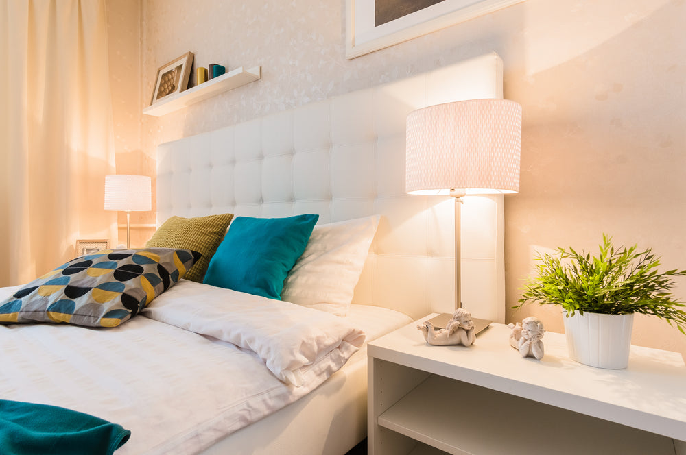 Two matching silver lamps on either side of a bed, with beautiful textured white lamp shades