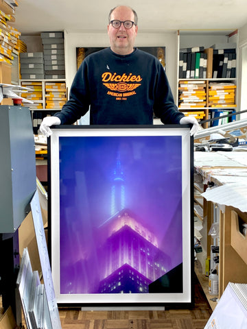 Richard Heeps in his home studio with a picture of New York.