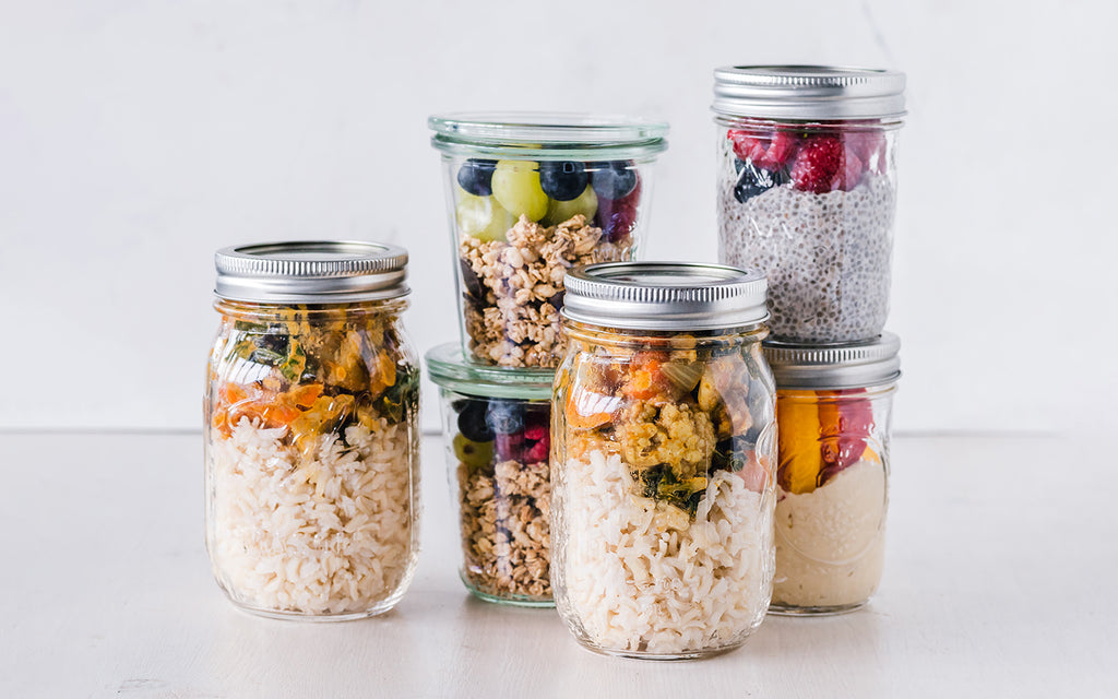 six mason jars filled with healthy foods for a weeks worth of meal preparation