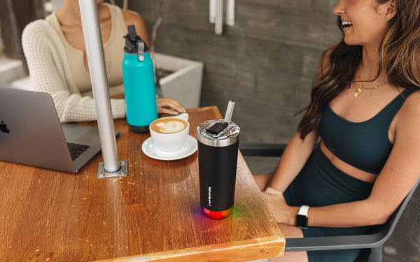 Two women enjoying coffee and HidrateSpark water bottles.