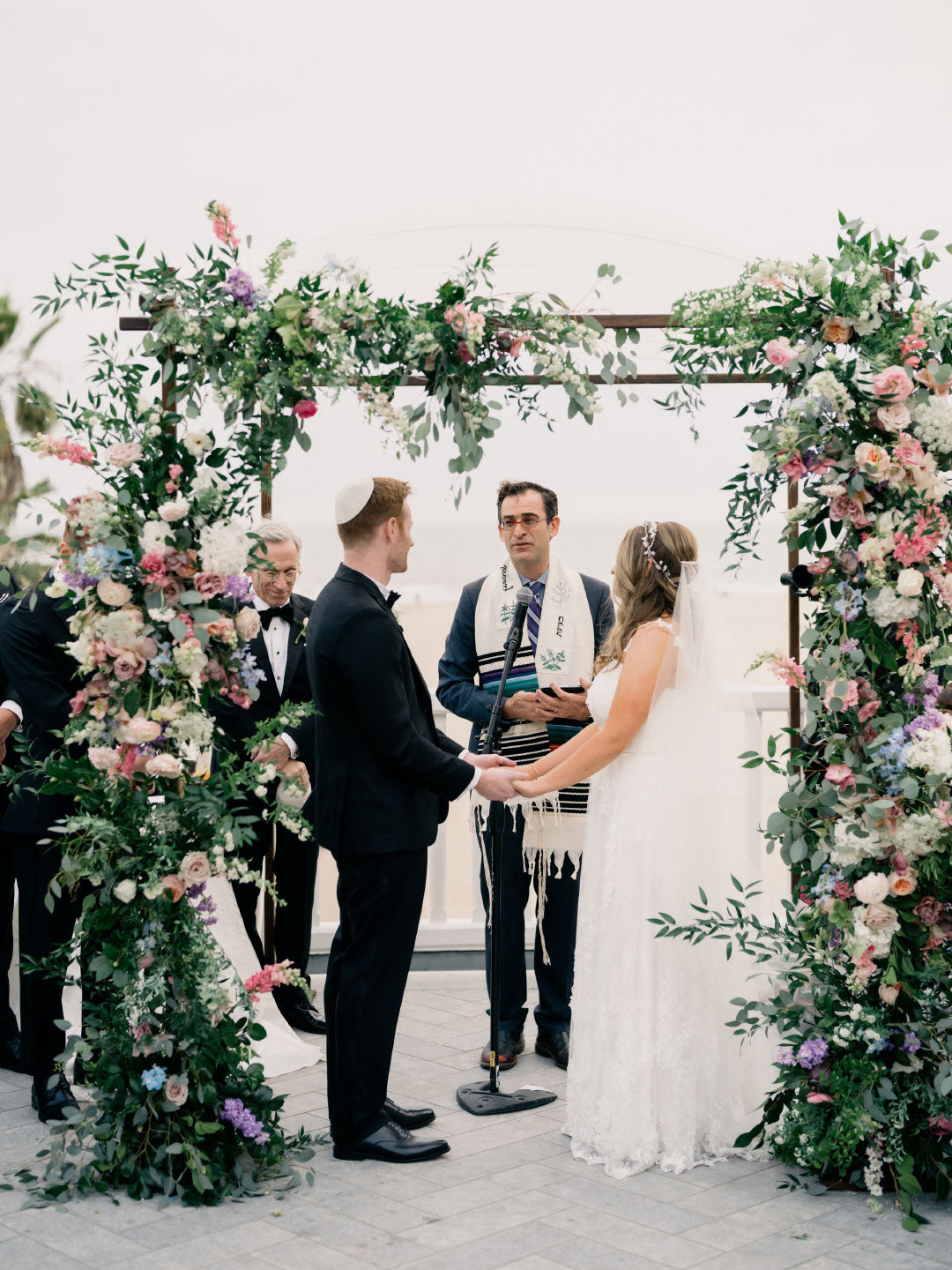 Groom and Bride under floral Chuppah