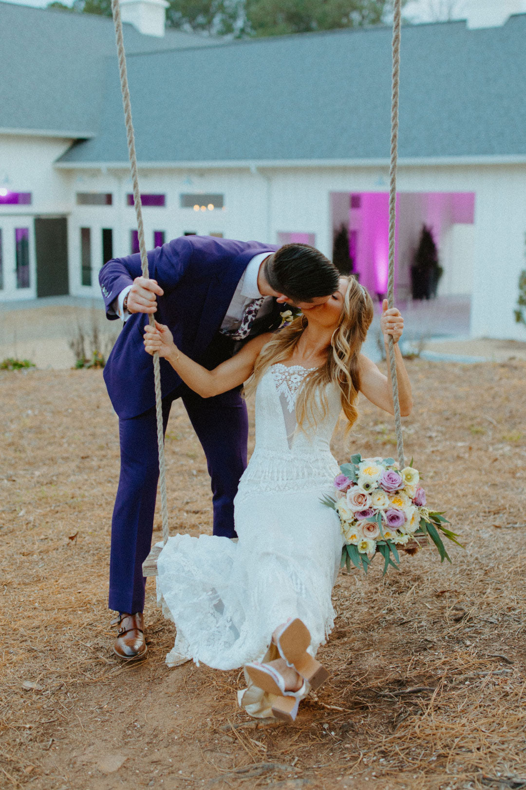 Groom Kisses bride while on swing