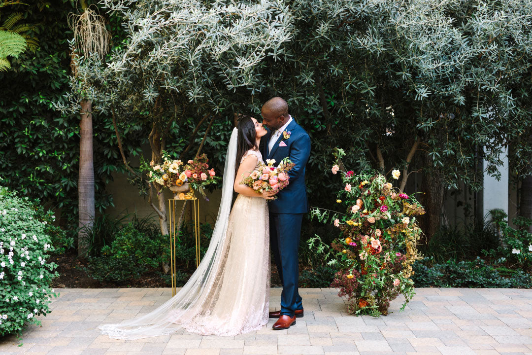 Bride and groom pose in front of floral bouquet