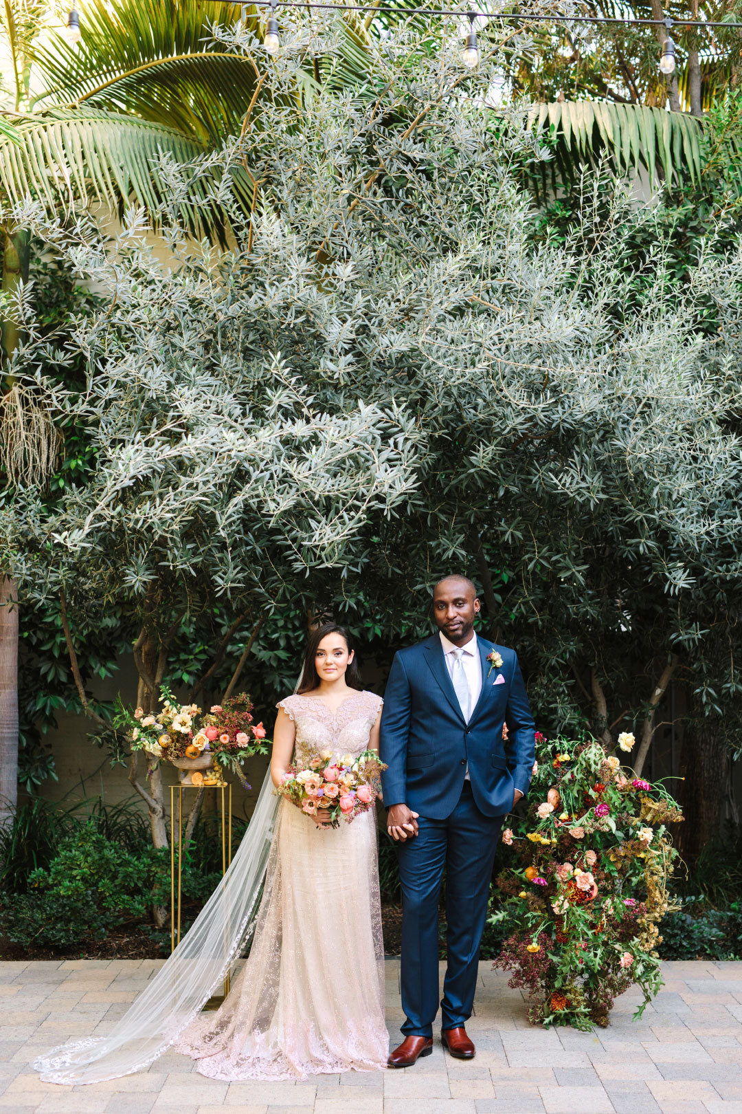 Bride wearing Aurora wedding dress by Claire Pettibone Groom in Blue Suit