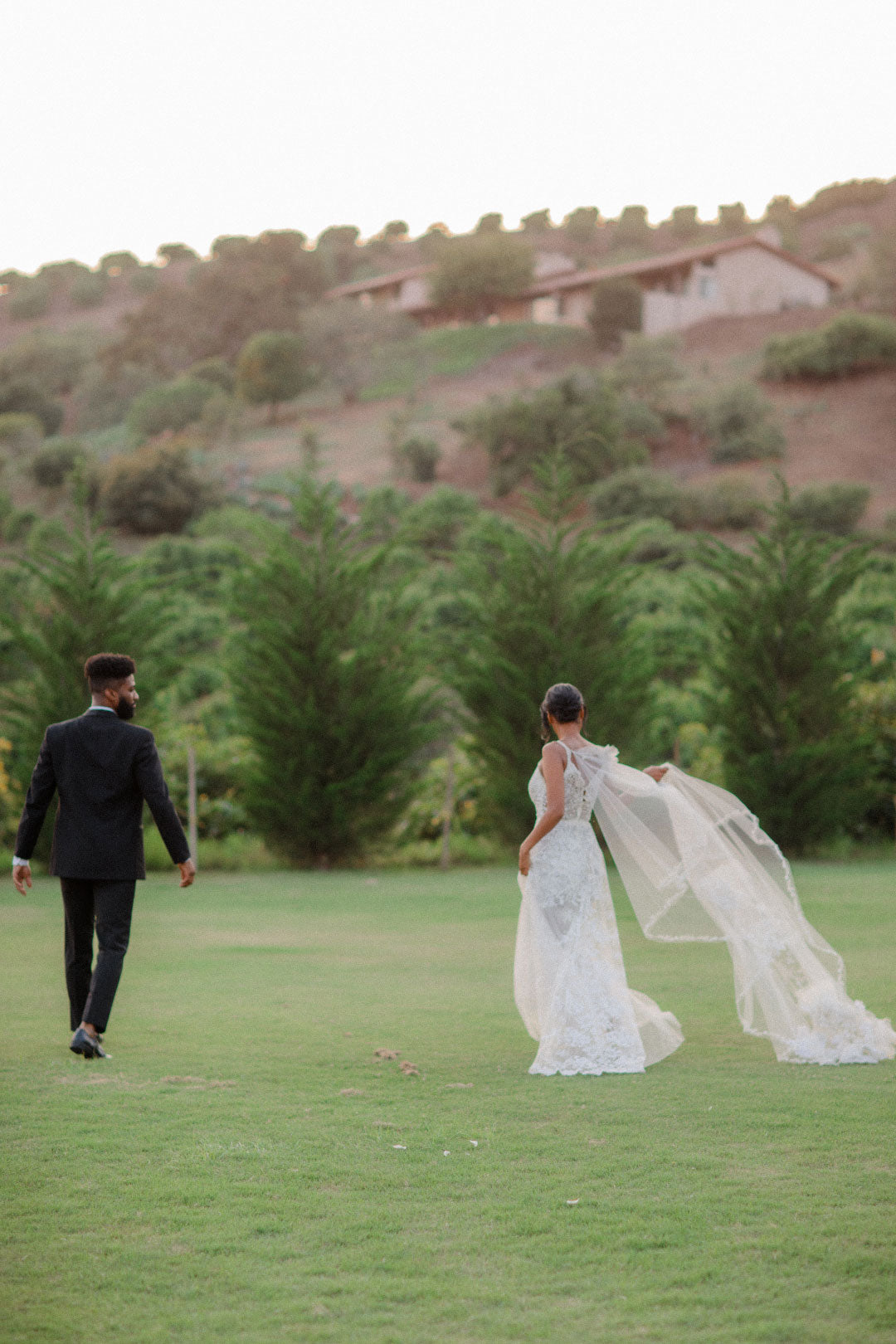 Bride and groom walking in wedding venue grass field