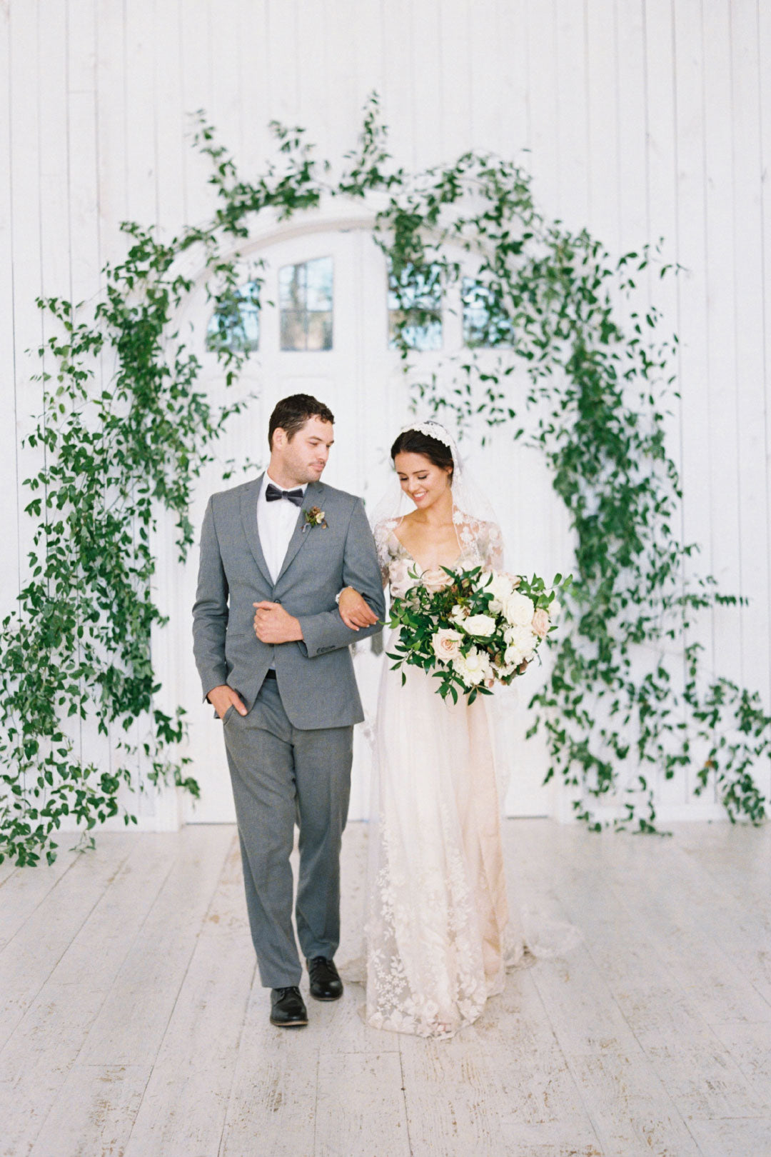 Bride and groom at floral and greenery arch