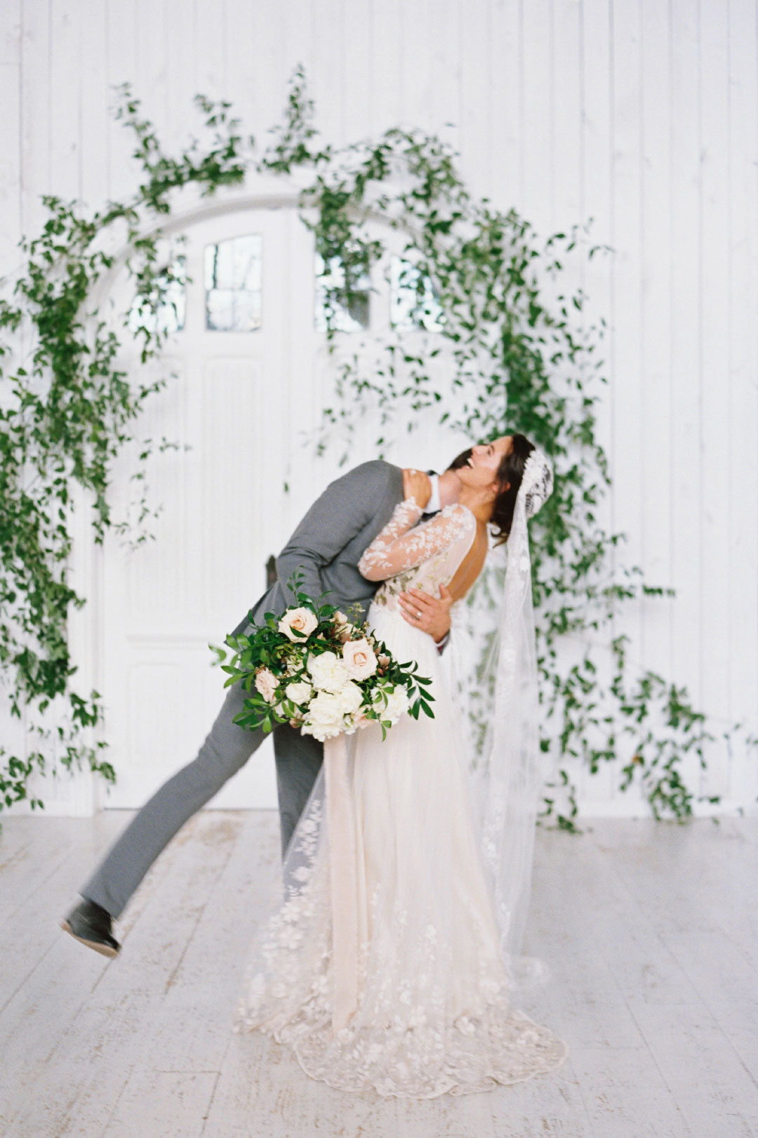 Bride and groom at floral and greenery arch