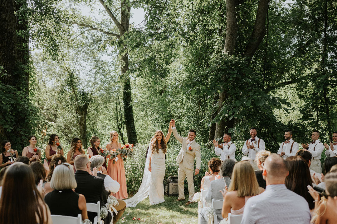 Bride and groom lift hands and celebrate after ceremony