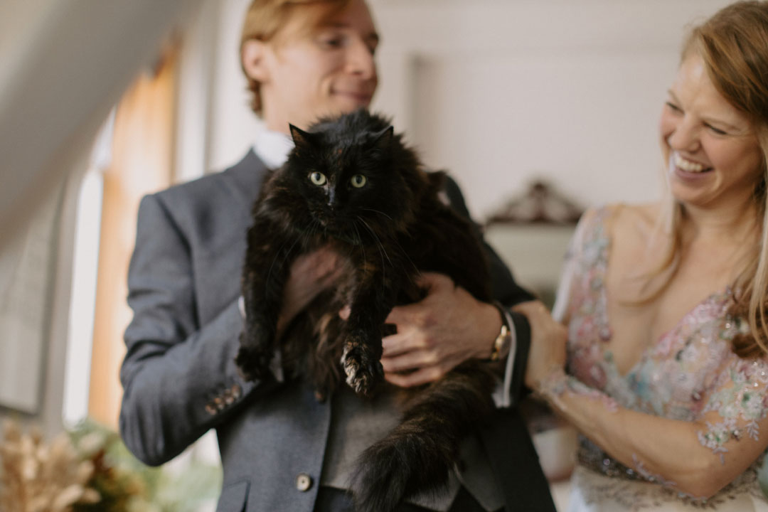 Groom holding cat and Bride is laughing