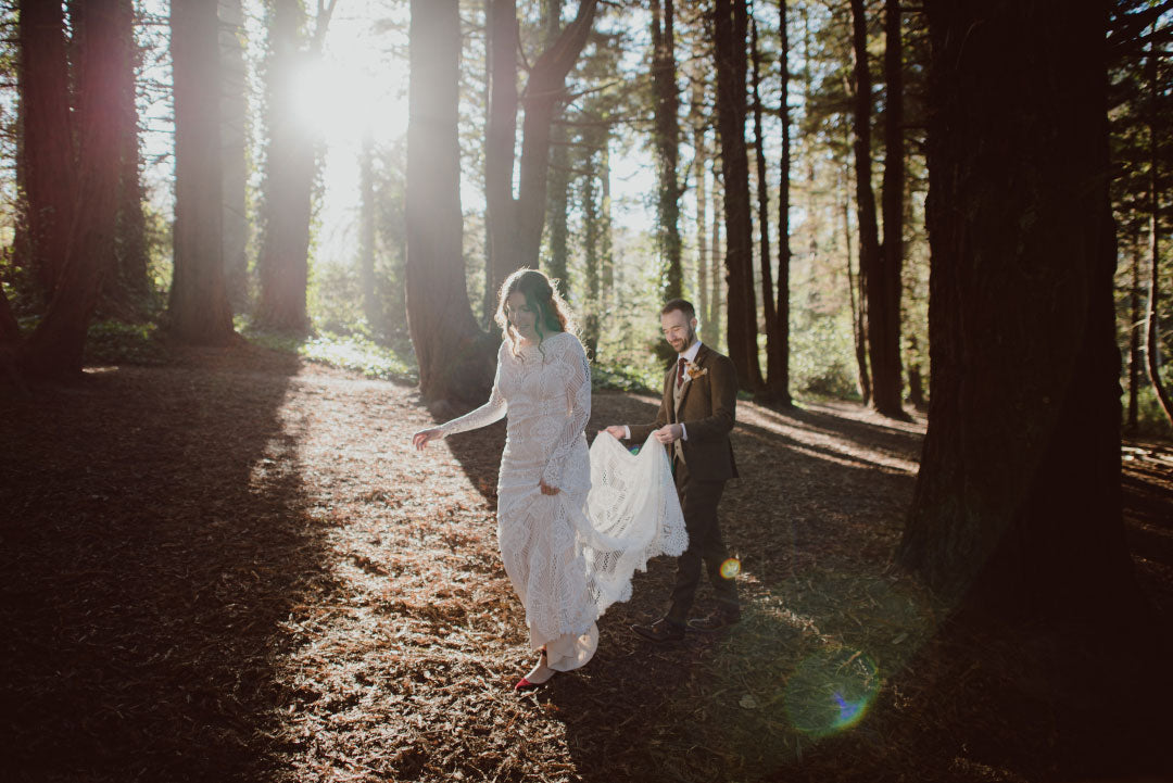 Bride and groom walking through forrest with sun beams