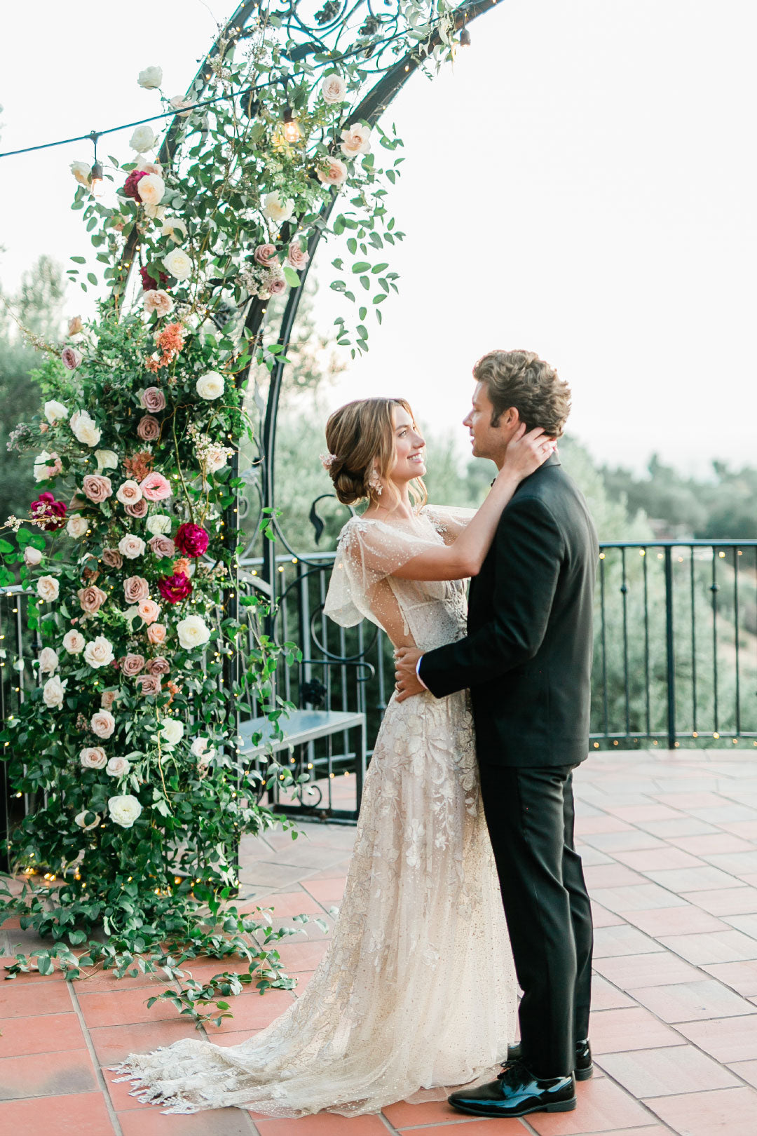 Bride and Groom embrace under wedding floral display