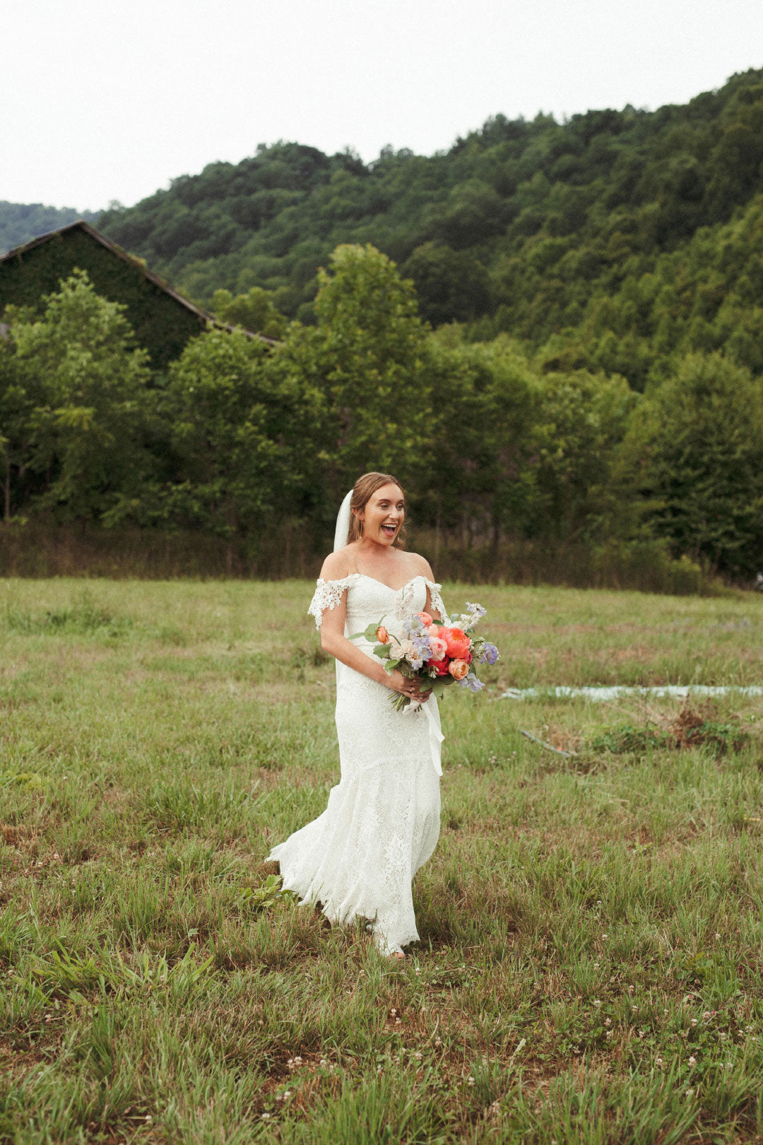 Bride holding wedding bouquet walking in field