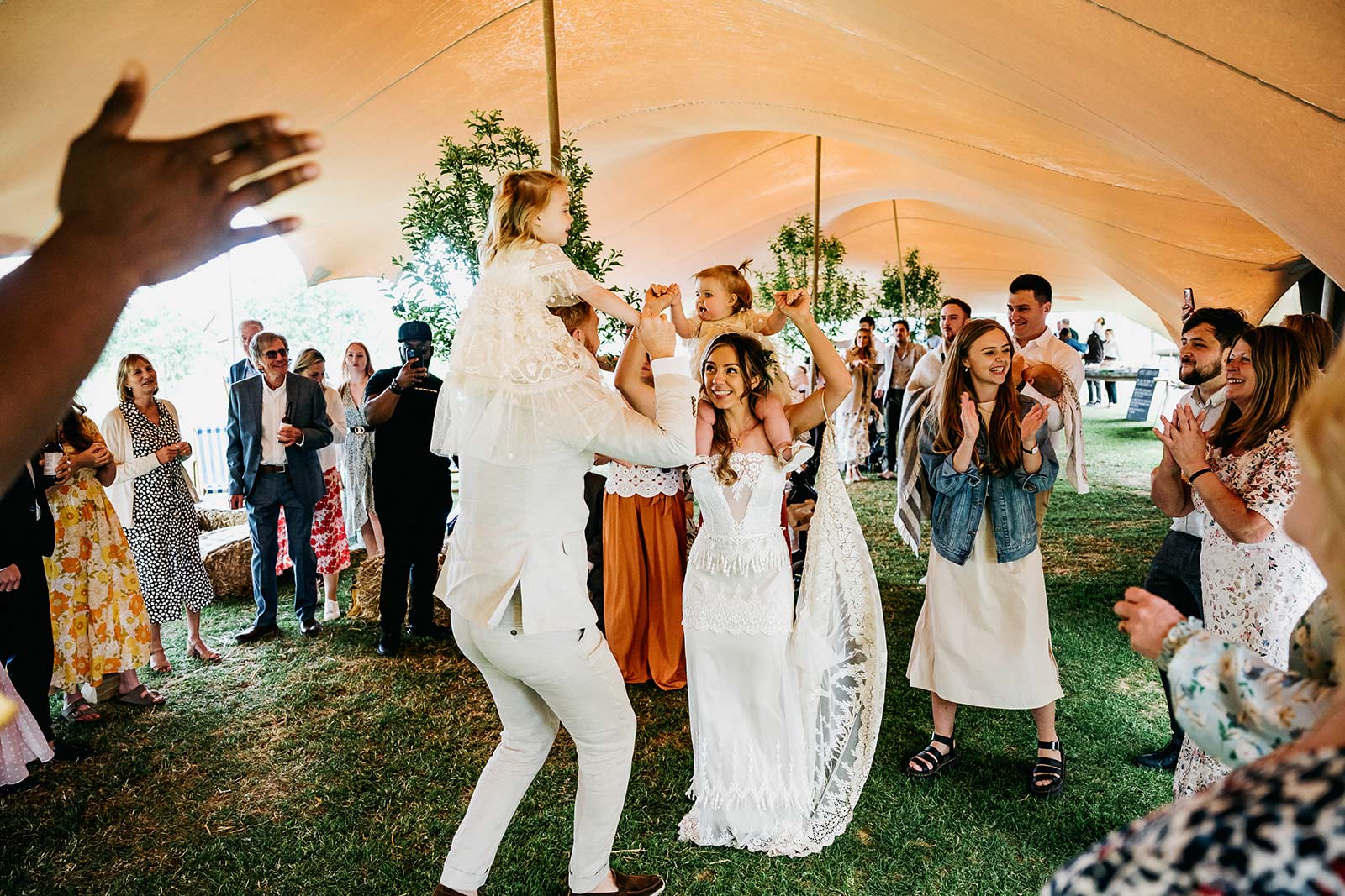 Bride and Groom dance while holding babies a wedding party