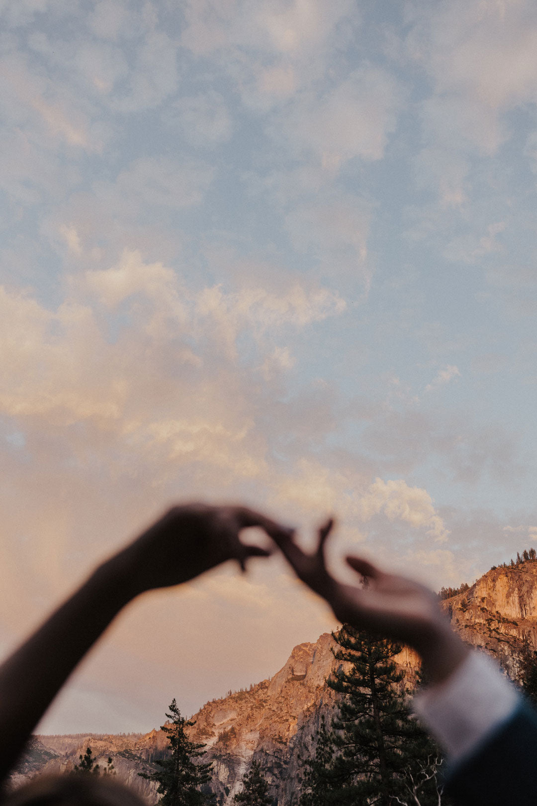 Hands touch with sky in background