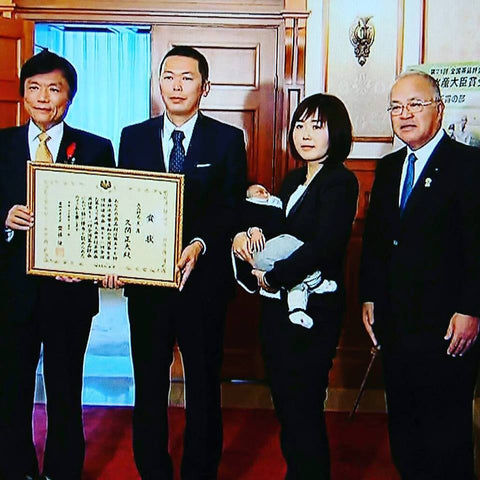 Masahiro Kuma (with his wife and newborn baby) receives the Minister's Award from Fukuoka Governor Hiroshi Ogawa