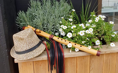 A native american flute lying next to a fedora had in a planter box
